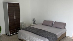 A bedroom with a bed, a wardrobe, a nightstand, and a lamp.