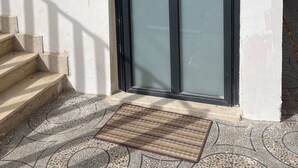 A modern building entrance with a glass door, a metal staircase, and a patterned floor.