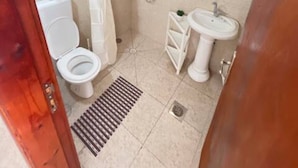 A small bathroom with a toilet, sink, and shower.