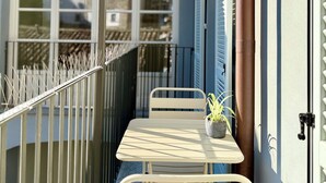 A narrow balcony with a table and chairs, a potted plant, a metal railing, and a wall-mounted light fixture. - Residenza Della Bollente II - Stylish cosy apartment in the heart of the town. (Acqui Terme)