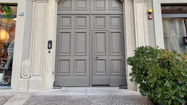 A building facade with a large, central double door, a small window above the door, and a balcony with metal railings. - Residenza Della Bollente II - Stylish cosy apartment in the heart of the town. (Acqui Terme)