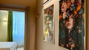 A hotel room with a bed, a painting of a floral arrangement, and a hallway leading to another room. - Residenza Della Bollente II - Stylish cosy apartment in the heart of the town. (Acqui Terme)