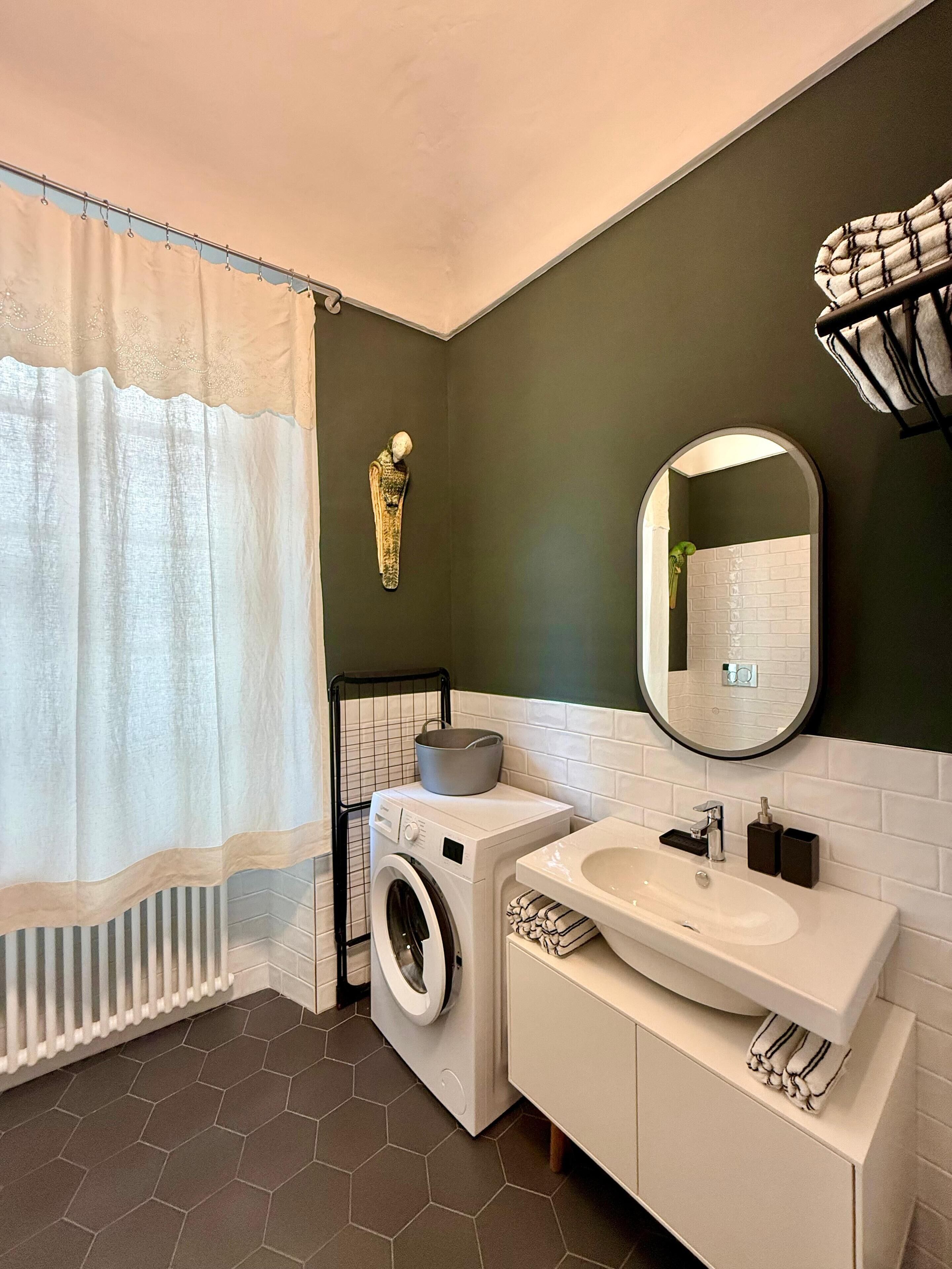A modern bathroom with a washing machine, a sink, and a mirror.