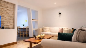 A modern living room with a sofa, coffee table, and a dining area with a table and chairs. - Peaceful 4-bedroom house in quaint stevenage perfect for families & contractors (Stevenage)