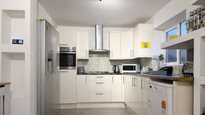 A modern kitchen with white cabinets, stainless steel appliances, and a built-in dishwasher. - Peaceful 4-bedroom house in quaint stevenage perfect for families & contractors (Stevenage)