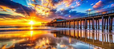 A pier extending into the ocean with a sunset in the background.