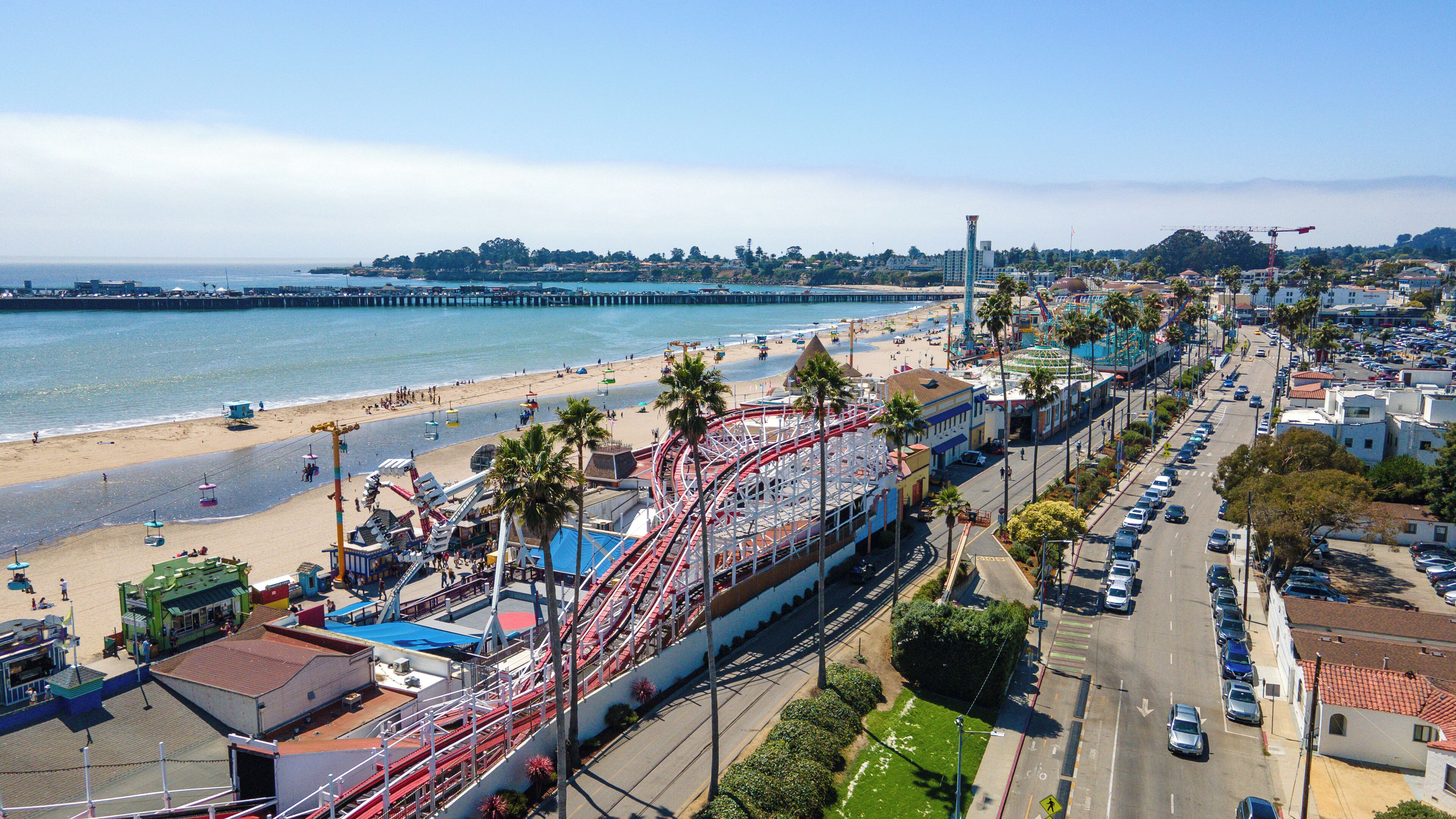 Un paisaje urbano costero con playa, parque de atracciones y calles.