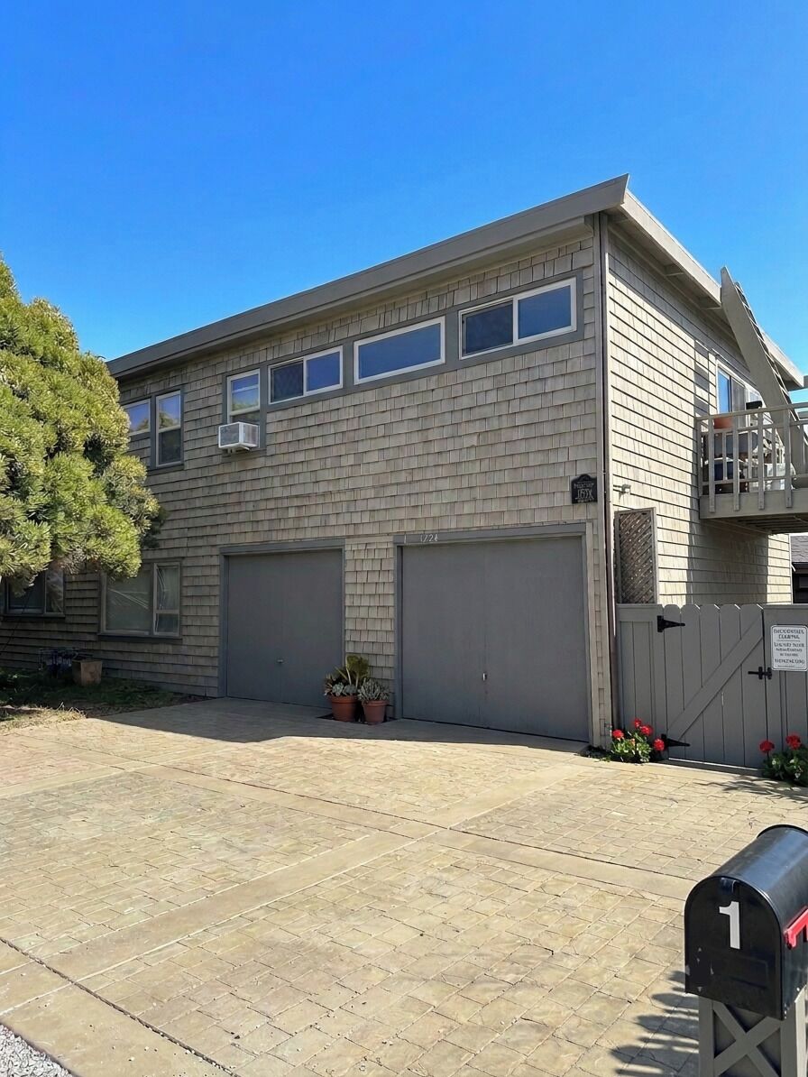 A two-story building with a garage, a small balcony, and a mailbox.