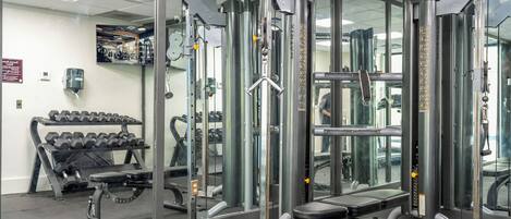 A gym with weightlifting equipment, a bench, and a rack of dumbbells.