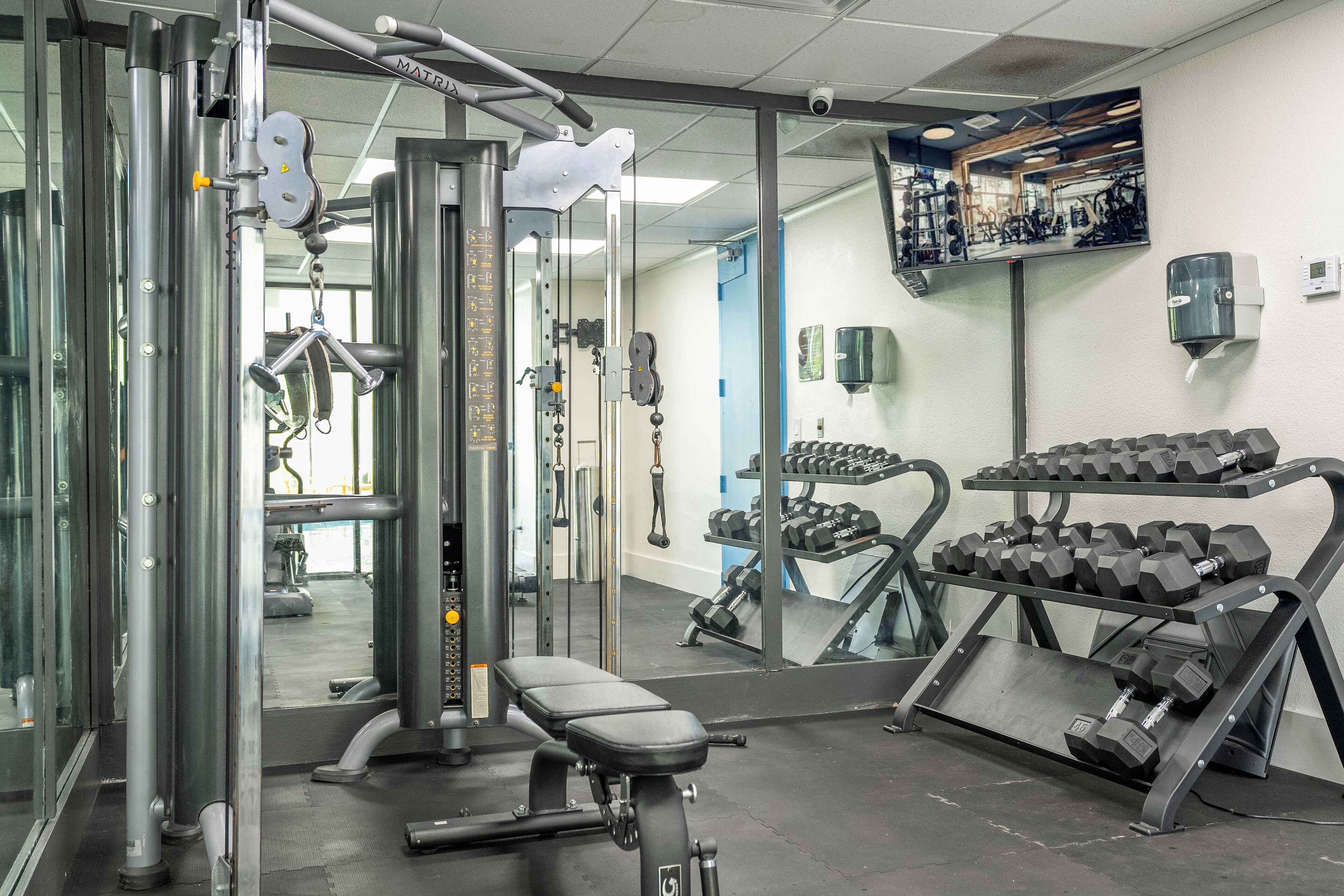 A gym with weightlifting equipment, benches, and dumbbells.