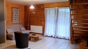 Ein gemütliches Wohnzimmer mit einer Couch, einem Couchtisch, einer Heizung und Holzwänden.
