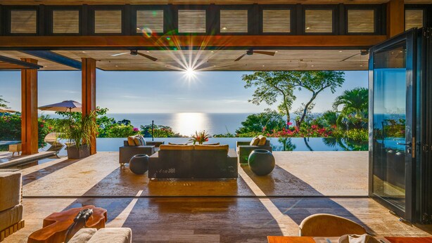An outdoor seating area with a view of the ocean, wooden furniture, and a ceiling fan. - Pacific Vistas Villa + Jungle View Casita - 2 Homes, Total Privacy, Mal Pais (Malpais)
