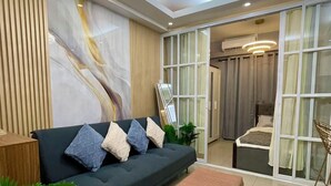 Ein modernes Wohnzimmer mit einem dunklen Sofa, einem beigen Hocker und einem großen abstrakten Gemälde an der Wand.