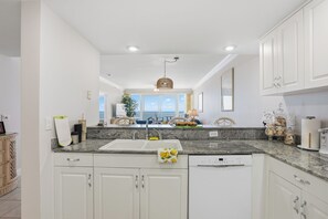 A modern kitchen with white cabinets, granite countertops, and a dishwasher. - Princess Condos - All Units Are Gulf Front & Direct Beach Access in PCB! (Panama City Beach)