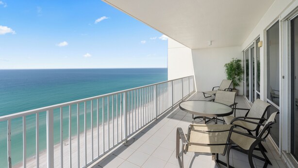 A balcony with a view of the ocean, a table with chairs, and a potted plant. - Princess Condos - All Units Are Gulf Front & Direct Beach Access in PCB! (Panama City Beach)