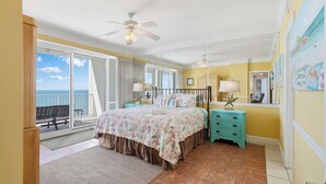 A bedroom with a bed, a nightstand, a ceiling fan, a window with a view of the ocean, and a balcony. - Beach & Gulf front Unit 1003 at Princess Condos 6415 Thomas Drive (Panama City Beach)