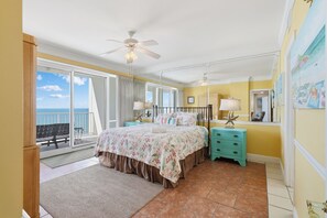 A bedroom with a bed, a nightstand, a ceiling fan, a window with a view of the ocean, and a balcony. - Beach & Gulf front Unit 1003 at Princess Condos 6415 Thomas Drive (Panama City Beach)