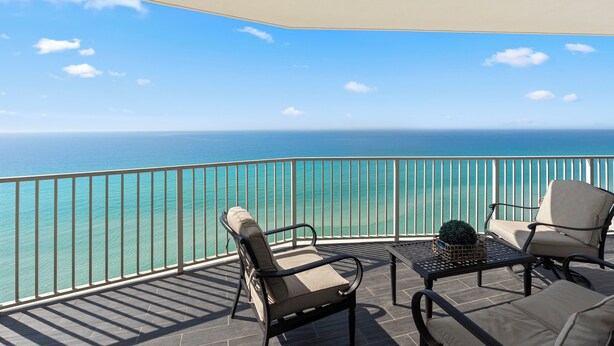 A balcony with two chairs and a table, overlooking a turquoise sea. - Princess Condos - All Units Are Gulf Front & Direct Beach Access in PCB! (Panama City Beach)
