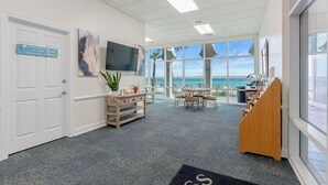 A spacious office with a large window, a wooden desk, a television, and a sign on the door. - Princess Condos - All Units Are Gulf Front & Direct Beach Access in PCB! (Panama City Beach)