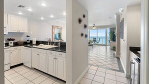 Een moderne keuken met witte kastjes, een zwart aanrecht en uitzicht op een balkon.