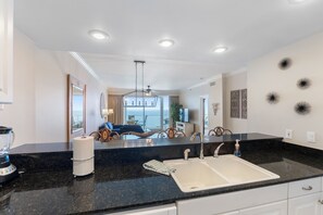 A modern kitchen with a black granite countertop, white sink, and a built-in blender. - Princess Condos - All Units Are Gulf Front & Direct Beach Access in PCB! (Panama City Beach)