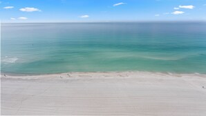 Een strand met helder turquoise water en een breed zandstrand.