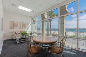 A conference room with a round table, chairs, a sofa, and artwork on the wall. - Princess Condos - All Units Are Gulf Front & Direct Beach Access in PCB! (Panama City Beach)