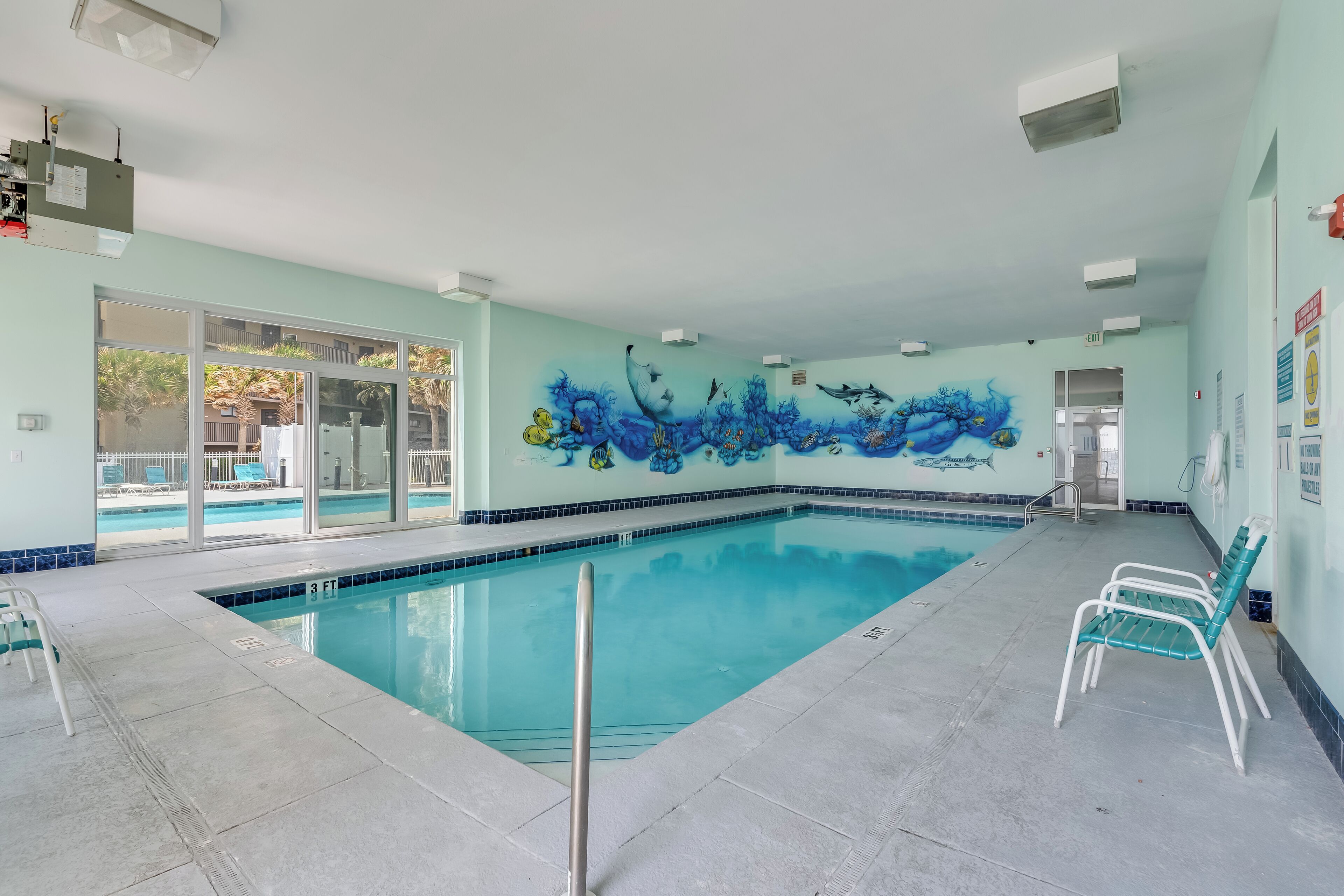 A swimming pool with a mural, clear glass doors, and a tiled floor.
