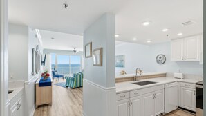 Een moderne keuken met witte kasten, een groot eiland en uitzicht op buiten.