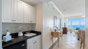 A modern kitchen with white cabinets, a black countertop, and a built-in dishwasher. - Princess Condos - All Units Are Gulf Front & Direct Beach Access in PCB! (Panama City Beach)
