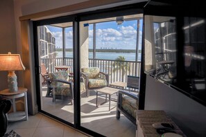 Ein Zimmer mit einer Schiebetür zu einem Balkon mit Sitzmöbeln und Blick auf das Wasser.