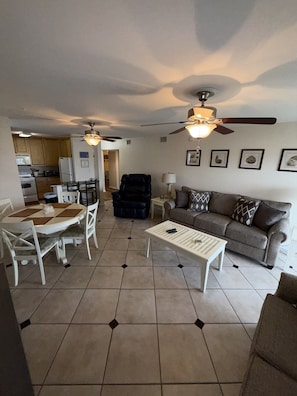 A living room with a sofa, coffee table, and dining area with chairs and a table. - B 11 Sundown Condominiums (Pensacola)