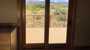 Blick vom Balkon mit Holzboden, Metallgeländer und einer Tür zu einem Raum mit einem Holzkasten.