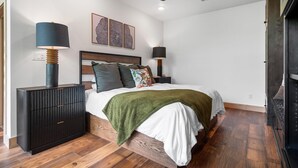 A bedroom with a bed, bedside tables, a ceiling fan, and a wall-mounted artwork. - The Miller at In the Trees Luxury Resort, Hot Tub, Fireplace, Mountaintop (Hot Springs National Park)