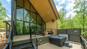 A modern outdoor deck with a hot tub, a staircase, and a glass-enclosed patio area. - The Miller at In the Trees Luxury Resort, Hot Tub, Fireplace, Mountaintop (Hot Springs National Park)