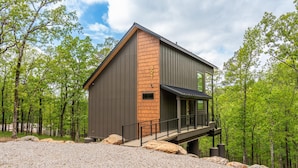 A modern building with a wooden accent wall, a balcony, and a gravel driveway surrounded by trees. - The Eagle at In the Trees, Hot Tub, Mountaintop, Fireplace, Luxury (Hot Springs National Park)