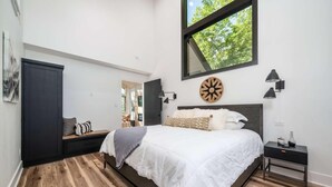 Un dormitorio con una cama grande, un armario, una mesita de noche, una lámpara y un reloj en la pared.
