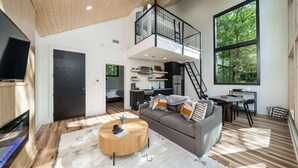 Amplia zona de estar con techo alto, habitación entre pisos, cocina y comedor.
