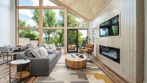 A modern living room with a large TV, comfortable seating, and a fireplace. - The Grey Horse at In the Trees Luxury Resort, Mountaintop, Hot Tub, Outdoor Fireplace (Hot Springs National Park)