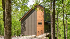 Une cabane aux murs en bois et au toit en métal, entourée d’arbres.