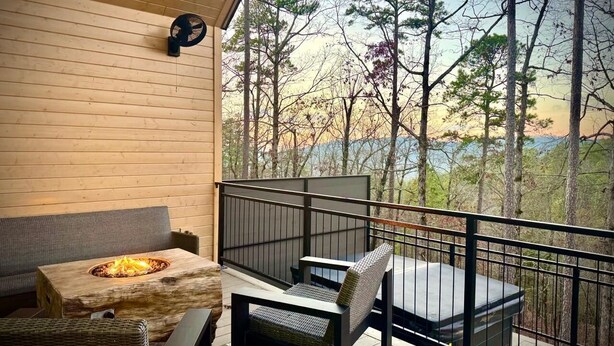 Un balcon doté d’un foyer extérieur, de sièges et offrant une vue sur des arbres et une étendue d’eau.