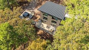 Een moderne cabin met een terras, omringd door dicht bos.