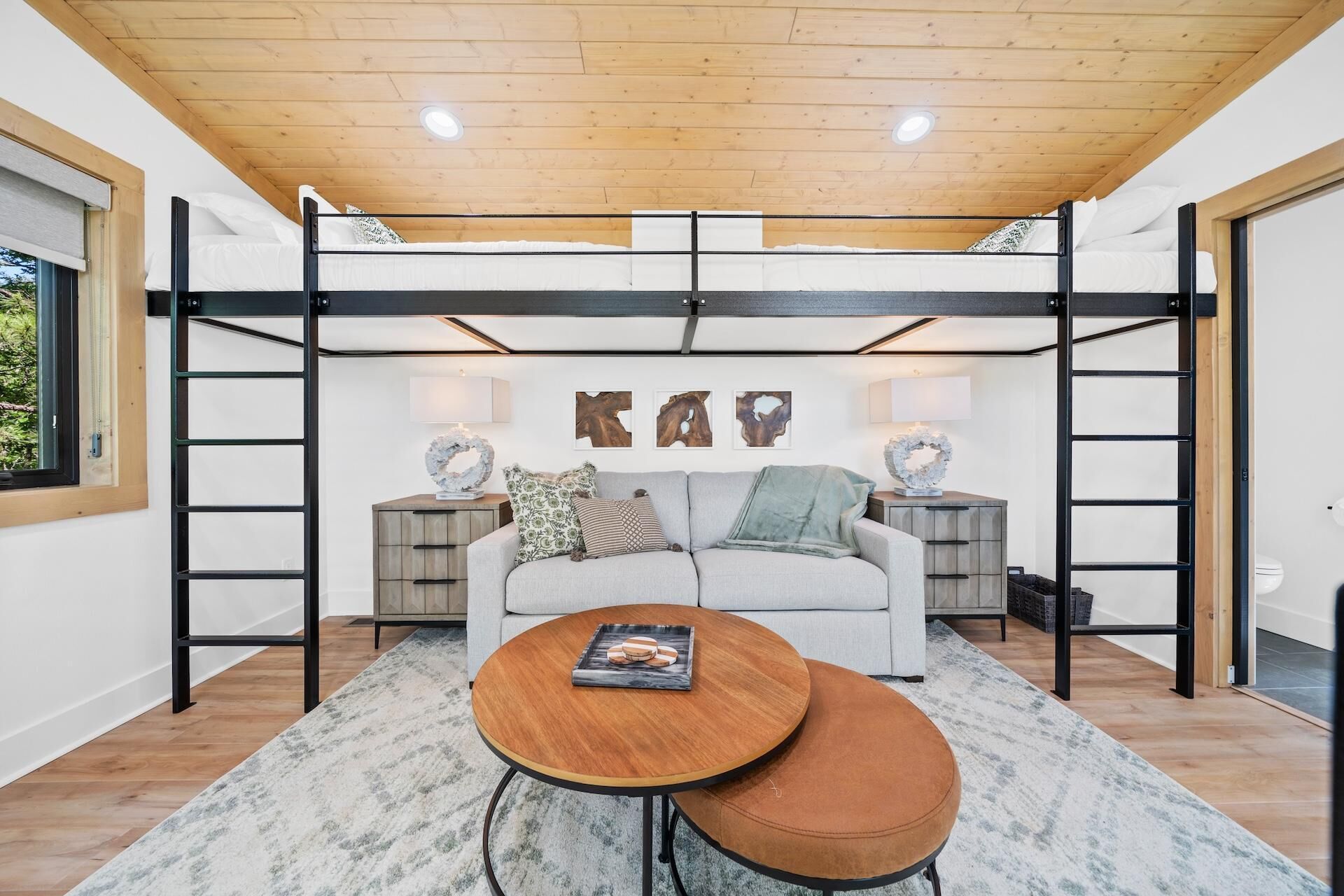Une chambre de style loft moderne, avec un lit superposé, un canapé, une table basse et des œuvres d’art décoratives au mur.