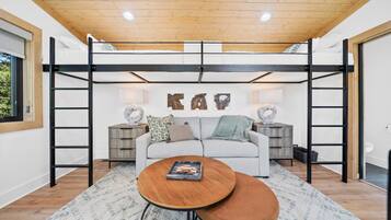 Une chambre de style loft moderne, avec un lit superposé, un canapé, une table basse et des œuvres d’art décoratives au mur.