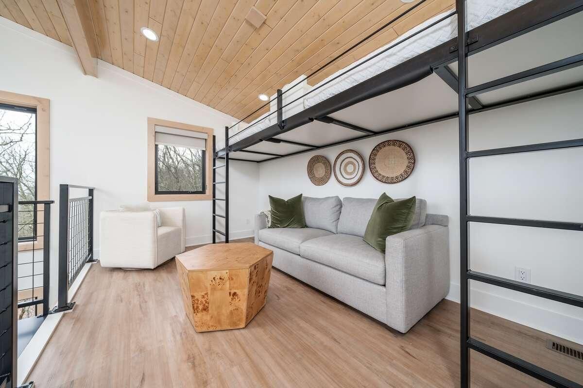 Een moderne woonkamer met een slaapverdieping, een bank, een salontafel en decoratieve borden aan de muur.