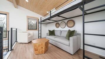 Een moderne woonkamer met een slaapverdieping, een bank, een salontafel en decoratieve borden aan de muur.