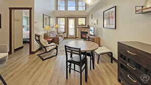 A spacious living area with a dining table, chairs, a sofa, and a fireplace. - Top-Floor Silver Rock 1BR – Comfort in Every Stay (Fernie)