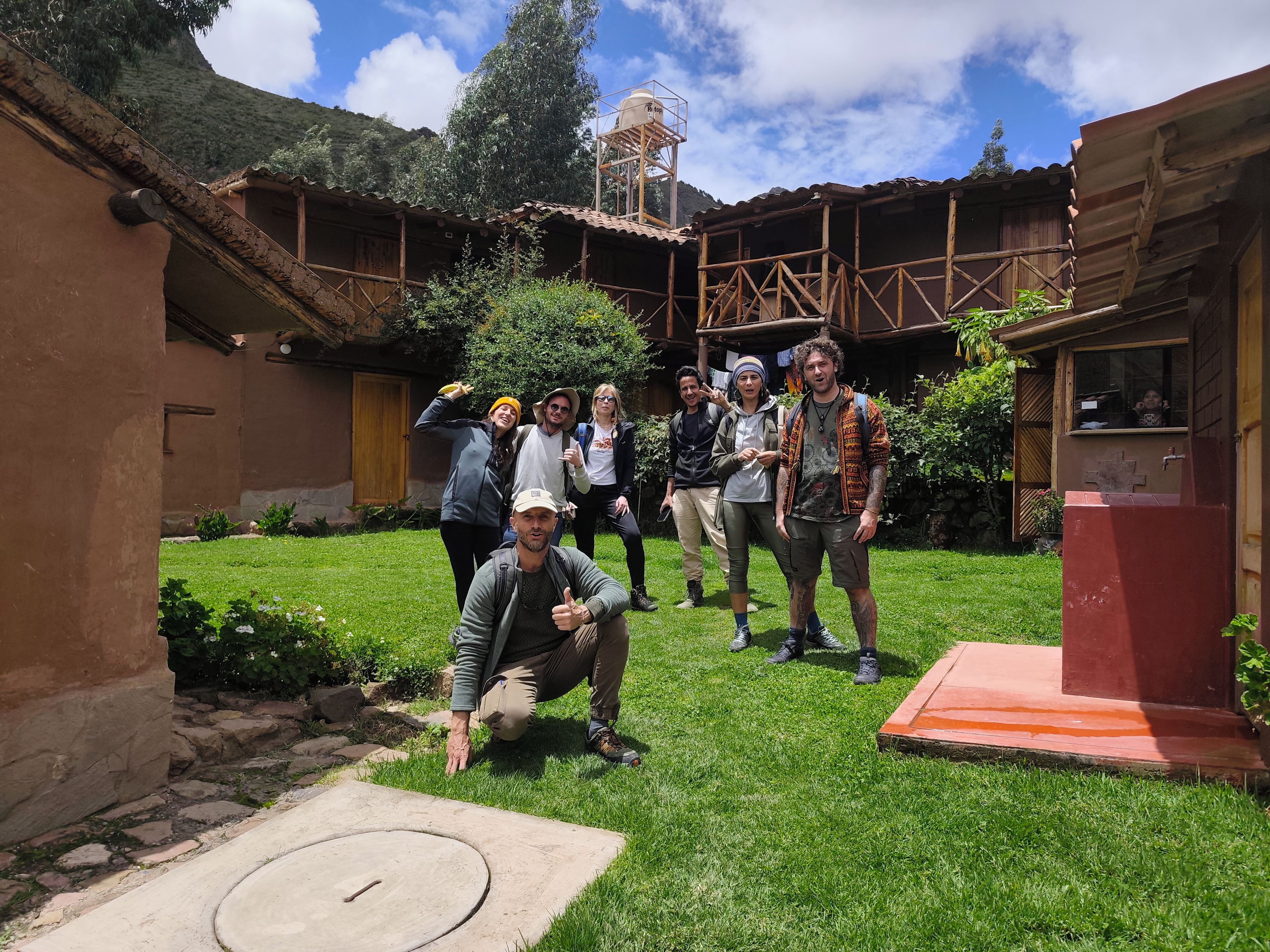 Un patio con un edificio rústico, una torre de agua y un grupo de personas.