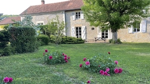 A stone building with a tiled roof, surrounded by a well-maintained lawn and flowering plants. - Le Clos Embelli - ROUVRES LES VIGNES (ROUVRES LES VIGNES)