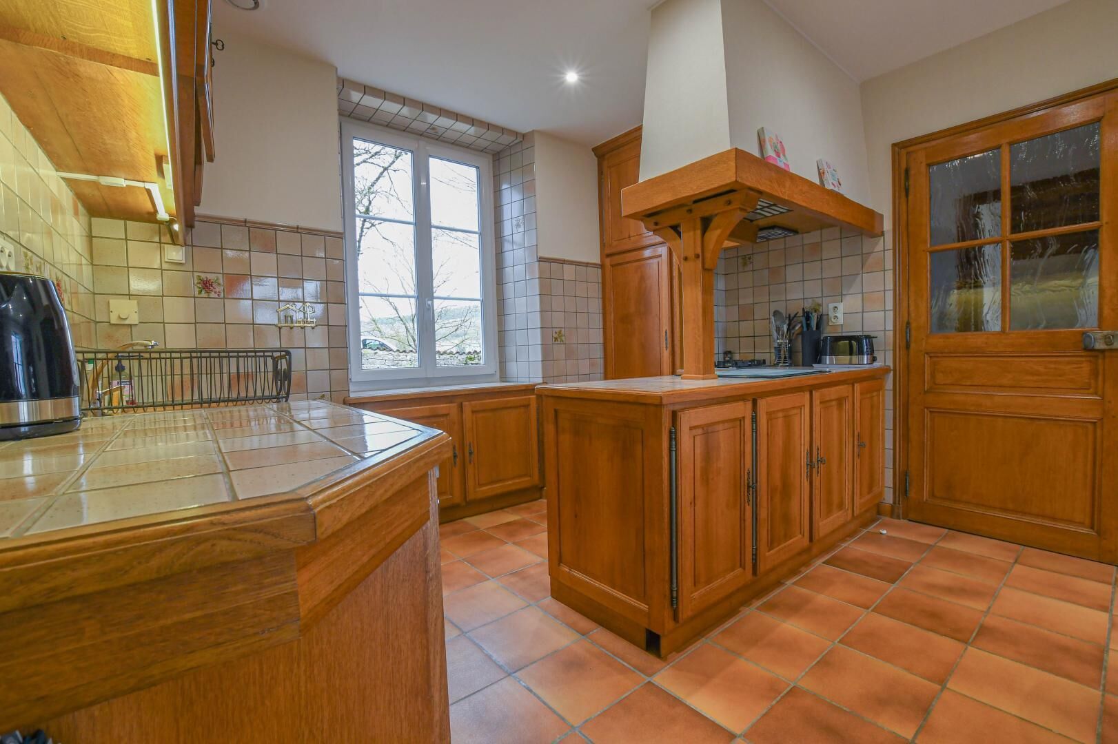 A kitchen with wooden cabinets, a tiled backsplash, and a window providing natural light.
